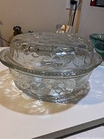Clear glass casserole dish with patterned fruit design lid, shown from side.