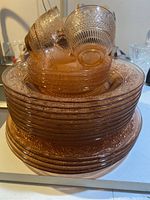 Stacked pink Depression glass dinner plates, soup bowls, side plates, and teacups showing texture and pattern details