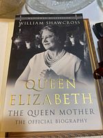Book cover of 'Queen Elizabeth The Queen Mother: The Official Biography' by William Shawcross, featuring a black and white photo of the Queen Mother.