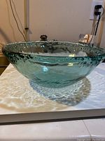 Full side view of the green textured glass mixing bowl on a white surface.