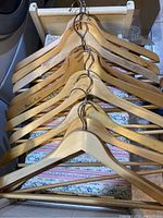 Overview photo showing eleven wooden hangers stacked in a row with metal hooks visible, one hanger stamped 'Canadian Pacific'.