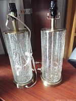 Photo showing both crackle glass lamps side by side with visible brass bases, tops, and attached cords.