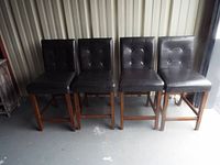 Four dark brown upholstered high chairs with wood legs arranged side by side, showing the full set