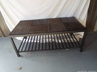 Full view of the rectangular coffee table from an angle, showing metal frame, tile-style top, and slatted lower shelf.