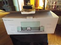 Photo of the Cricut Explore Air 2 box showing the opened package with the machine's image and features.