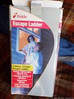 Box with brand and product information showing the Kidde Escape Ladder and illustration of use.