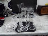 Wide view showing multiple assorted cut glass and crystal pieces including various bowls, glasses, candy dishes, and decorative items on a table surface.