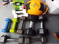 Various dumbbells and a 5 lb medicine ball on floor, showing condition and types of weights.