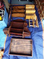 Mixed assortment of wooden shelves, trays, and organizer units arranged on blue fabric.
