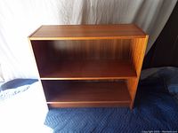 Full front view of pine bookcase showing two shelves and overall rectangular shape with wood grain finish.