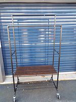 Full view of the rolling rack, showing the black metal frame and wooden bottom shelf.