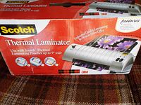 Boxed Scotch Thermal Laminator, showing branding and laminator image alongside features and specifications.