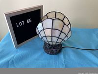 Clam shell table lamp positioned on blue cloth beside a board showing lot number