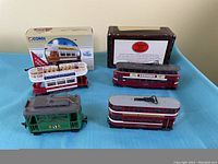 Photo of all five models including four double decker buses and one train car, some with original packaging.