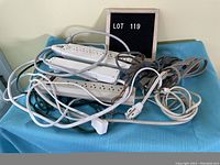 Lot of extension cords and power bars piled on a blue cloth with a sign 'LOT 119'