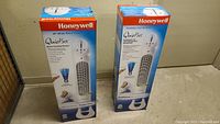 Photo showing two Honeywell 40 inch QuietSet tower fans in original packaging, standing upright side by side.