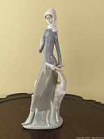 Front view of Lladro porcelain figurine depicting woman with scarf and dog standing beside her on a small base