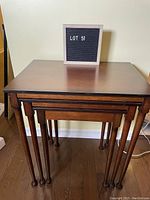 Three wooden nesting tables nested together front view