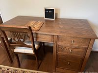 Front view of the oak desk and antique chair showing desk drawers and chair upholstery condition.