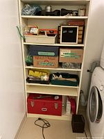 Shelf with various labeled boxes, plastic trays, and a red metal toolbox below, containing assorted household repair tools and parts.