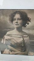 Close-up of framed portrait photo of young woman in vintage dress with floral adornments in hair