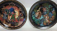 Photo showing two Russian legend hand painted collector plates featuring detailed folk art scenes with gold decorative borders.