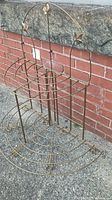 Full view of vintage metal folding plant stand showing decorative leaves and semi-circular wire shelves