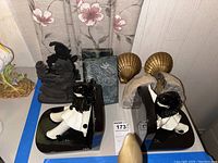Overall view of the decorative bookends set showing clown figure bookends alongside golden shell bookends, geode, metal figurine and Asian stone piece