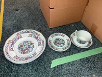 Full view of plates, salad plate, tea cup and saucer with floral red and blue Calyx Ware pattern on ironstone.
