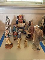 Overview photo showing 9 clown figurines of varying sizes, including a clown playing accordion and clowns with hats and props.
