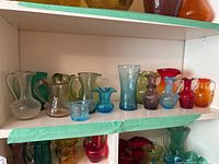 Shelf displaying a collection of 15 mini crackle glass vases and pitchers in different colors and shapes.