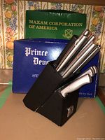 Photo showing Prince Devonshire stainless steel cutlery set inside black block with original blue box behind and Maxam Corporation box visible.