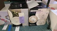 Two boxes of Stoneware Violet 20-piece dinnerware sets with floral pattern, boxed and unopened.