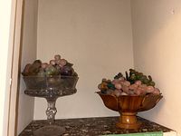 Two bowls with faux marble grape clusters, one glass and one wooden bowl.