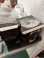 Overall view of glassware set with bowls and plates stacked on boxes, showing clear textured crystal glass and etched floral pattern.