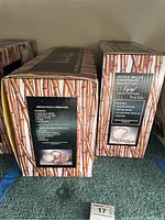 Photo showing two boxed Nicole Miller porcelain dinnerware sets in original packaging with white bamboo patterned artwork mimicking bamboo stalks.