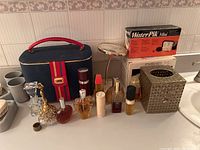 Full view of perfume bottles, makeup case, tissue box cover, mirror, and Water Pik Mini box