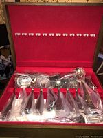 Set of Salem stainless steel flatware in original red velvet-lined box, utensils in plastic wrap, showing dinner forks, knives, and spoons.