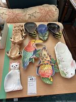 Overview of all ceramic spoon rests including bear, pear, flower, bird, cat, and bunny designs on a table.