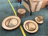 Set of plates, bowls, and mugs on carpet floor showing all pieces stacked separately
