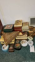 Photo showing a collection of fifteen assorted trinket and keepsake boxes in various shapes and designs, stacked and arranged on the floor.