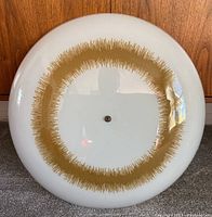 Top-down view of the round white glass ceiling light showing the central gold textured ring design and central fastening knob.