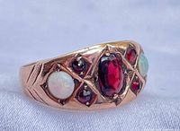 Oblique view showing entire ring face with central garnet and opals