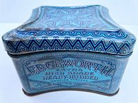 Photo showing the top and front side of the Edgeworth tobacco tin highlighting decorative blue and light blue star design and text.
