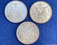 Reverse sides of the three Canadian 50 cent coins showing the Canadian coat of arms and years 1960, 1961, 1963.