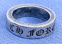 Close-up photo of silver-tone ring showing inner band markings 2003 .925 and textured finish.