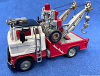 Side and angled views of vintage Holmes Wrecker tow truck showing red and white die cast metal body, detailed tow boom with pulley cables and hooks, spare tire, and side ladder.