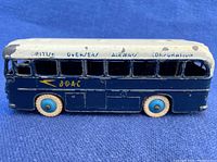 Side view of Dinky Toys BOAC Airport Bus showing blue body, white roof with British Overseas Airways Corporation lettering, white tires with blue hubs, and paint chips.