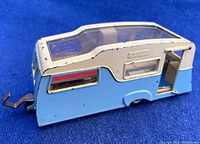 Side angle showing blue and cream caravan body with missing side door and tow hitch.