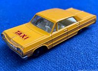 Close-up image showing front side and 'TAXI' decal on hood of yellow die cast Chevrolet Impala taxi toy.